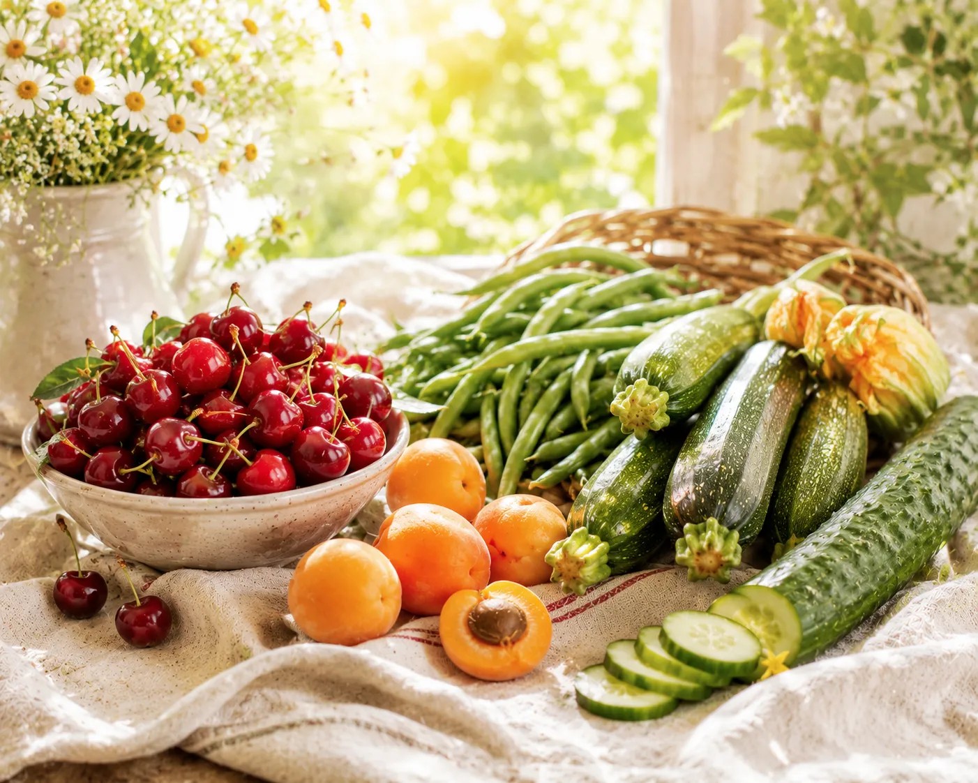 Table de début d'été garnie de cerises, d'abricots, de courgettes, de haricots verts et d'un concombre dans une lumière dorée